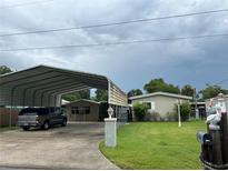 Charming single-story home with covered parking, lush lawn, and tasteful landscaping at 24505 Snail Rd, Astor, FL 32102