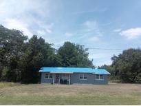 Quaint single-story home with a light gray exterior and a blue tarp roof, surrounded by lush greenery at 2822 S Dean Rd, Orlando, FL 32825