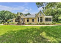 Charming yellow home with a manicured lawn and inviting front porch, perfect for relaxing outdoors at 3450 Ohio Ave, Sanford, FL 32773