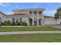 Stunning two-story home with a tile roof, columns, and a well-manicured lawn and garden at 3869 Shoreside Dr, Kissimmee, FL 34746