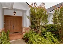 Inviting covered front entryway featuring double doors, brick accents, and lush landscaping at 8044 Rural Retreat Ct, Orlando, FL 32819