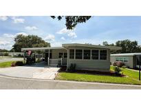 Charming single-story home with a carport and manicured lawn under a sunny sky at 103 Poinsettia Cv, Leesburg, FL 34748