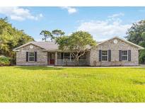 Charming single-story home with a brick facade, red door, covered porch, and lush green lawn at 1330 Englewood Dr, St Cloud, FL 34772