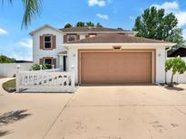 Charming two-story home boasts a large garage, well-kept landscaping, and a lovely white picket fence at 310 Dagama Ct, Kissimmee, FL 34758