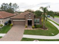 Beautiful single-story home features a brick paver driveway and manicured lawn with a palm tree at 4004 Prima Lago Cir, Lakeland, FL 33810