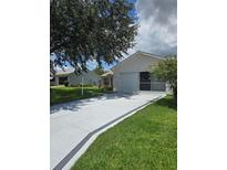 Charming single-story home with a manicured lawn, long driveway, and a screened-in garage at 527 San Pedro Dr, The Villages, FL 32159
