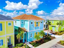 Brightly colored two-story home with a terracotta roof, palm trees, and well-manicured landscaping at 2968 Salted Rim Rd, Kissimmee, FL 34747