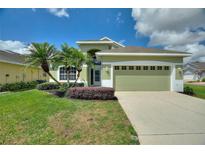 Inviting single-story home featuring a well-manicured lawn, a two-car garage, and vibrant landscaping at 705 Ashton Dr, Davenport, FL 33837