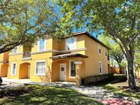 Charming two-story townhome with a sunny yellow exterior, inviting entrance and manicured landscaping at 2722 Impala Ln, Kissimmee, FL 34746