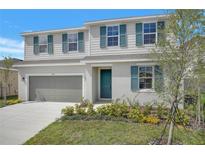 Charming two-story home with blue shutters, a well-manicured lawn, and a gray two-car garage at 1715 Sugarbelle Cir, Mascotte, FL 34753