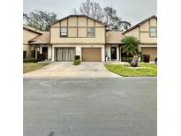 Tan two-story townhouse with brown garage doors and landscaping at 2031 Balboa Way, Kissimmee, FL 34741