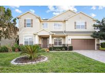 Charming two-story home featuring a well-manicured lawn, stone accents, and a welcoming entrance at 1387 Lexington Ave, Davenport, FL 33837