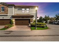 Beautiful exterior elevation showcasing a two-story townhome with a brick driveway and manicured landscaping at 8541 Spyglass Ln, Davenport, FL 33896