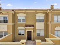 Townhouse with light brown stucco, red-tiled roof, white window frames, and covered entryway at 2774 Bella Vista Dr, Davenport, FL 33897