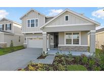 Two-story house with gray siding, stone accents, and a two-car garage at 2930 Sharp Rd, Kissimmee, FL 34744
