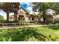 Two-story house with tan siding, a balcony, and palm trees in the front yard at 9210 Southern Breeze Dr, Orlando, FL 32836