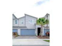 Modern 2-story townhome with light gray exterior, attached garage, and palm tree at 3379 Beaute Dr, Kissimmee, FL 34746