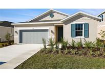 Tan house with gray garage door and teal shutters at 918 Heirloom Dr, Haines City, FL 33844