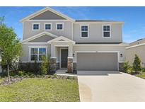 Charming two-story home featuring a manicured lawn, stone accents, and a two-car garage at 1635 Sugarbelle Cir, Mascotte, FL 34753