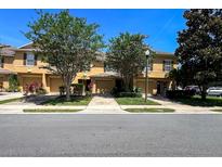 A sunny daytime shot of a tan two-story townhome with a front lawn and a tree-lined street at 721 Interlude Ln # 105, Orlando, FL 32824