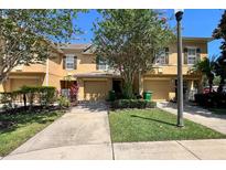 Beautiful two-story townhomes with a well-maintained lawn, mature tree, and individual driveways at 721 Interlude Ln # 105, Orlando, FL 32824
