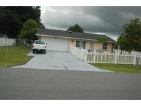 Ranch-style home with driveway, white picket fence, and mature landscaping at 267 Cranbrook Dr, Kissimmee, FL 34758