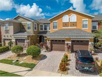 Three-story townhouses with brown garages, and landscaped yards at 9532 Silver Buttonwood St, Orlando, FL 32832