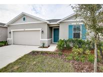 One-story house with gray siding, teal shutters, and a two-car garage at 1634 Sugarbelle Cir, Mascotte, FL 34753