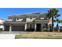 Two-story tan home with a two-car garage, a tiled roof, a well-manicured lawn, and a palm tree in the front yard at 3801 Sonoma Blvd, Kissimmee, FL 34741