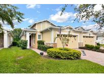 Tan two-car garage villa with red door and landscaped yard at 2453 Yellow Brick Rd, Saint Cloud, FL 34772