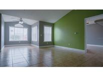 An open living room featuring tile flooring, ceiling fan, and bright windows for natural light at 2217 Grand Cayman Ct # 1233, Kissimmee, FL 34741