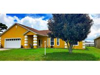 Charming yellow single-story home featuring a well-manicured lawn and a two-car garage at 9549 Sw 53Rd Cir, Ocala, FL 34476