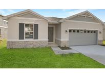 Newly constructed home with gray siding, stone accents, and a two-car garage at 4212 Sawtooth Ct, Tavares, FL 32778