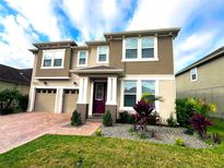 Two-story home with a two-car garage, red brick drive, and manicured landscaping at 8118 Platts Ave, Orlando, FL 32832