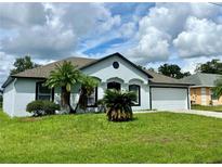 Newly painted house with a well-maintained lawn and a two-car garage at 413 Cardinal Ct, Kissimmee, FL 34759