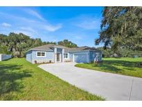 Charming single-story home with a blue exterior, stone accents, well-manicured lawn, and a long driveway at 319 Water Shore Dr, Leesburg, FL 34748