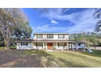 Two-story house with white siding, brown double doors, and a landscaped lawn at 32122 Hickory Ln, Sorrento, FL 32776