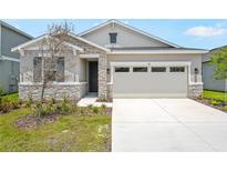 Charming single-Gathering home with a two-car garage, stone accents, neutral paint colors, and a well-maintained lawn at 196 Flag Lilly Ln, Umatilla, FL 32784