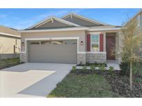 Charming home featuring stone accents, a two-car garage, and a well-manicured lawn at 207 Bull Frog Ln, Umatilla, FL 32784