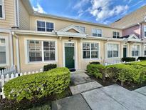 Inviting exterior of a two-story townhome with manicured landscaping and a white picket fence at 4019 Venetian Bay Dr # 105, Kissimmee, FL 34741