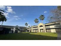 A charming building featuring a grassy courtyard and palm trees against a clear blue sky at 5245 W Irlo Bronson Memorial Hwy # 244, Kissimmee, FL 34746