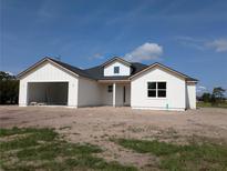 New construction shows a charming white home with an attached garage, and a dormer window detail at 3664 Cord Ave, St Cloud, FL 34772