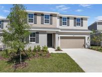 Charming two-story home with a manicured lawn, neutral color palette, and an attached two-car garage at 1667 Sugarbelle Cir, Mascotte, FL 34753