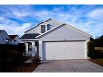 Two-story house with gray siding, white garage door, and landscaping at 523 Royal Ridge Dr, Davenport, FL 33837
