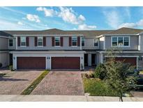 Three-unit townhome building with attached garages and brick pavers at 1292 Wispy Cypress Dr, Kissimmee, FL 34746