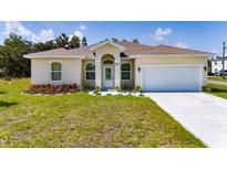 Charming single-story home with a well-manicured lawn, landscaped flower bed, and attached two-car garage at 1415 Orlando Way, Kissimmee, FL 34759