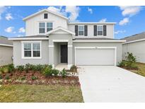 Charming two-story home with a gray stucco exterior, two car garage, and nicely landscaped front yard at 5406 Catmint Dr, Lake Hamilton, FL 33851