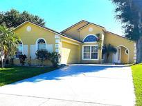 Charming home featuring a two-car garage, well-manicured lawn, and an inviting arched entryway at 2112 Fish Eagle St, Clermont, FL 34714