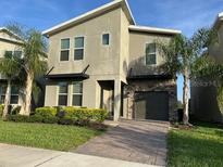Two-story home with a well-manicured lawn, lush landscaping, and brick paved walkway to the front door at 712 Whistling Straits Blvd, Davenport, FL 33896
