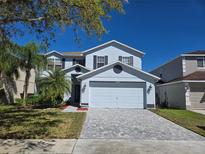Charming two-story home featuring a well-manicured lawn, gray brick driveway and attached two-car garage at 14716 Yorkshire Run Dr, Orlando, FL 32828